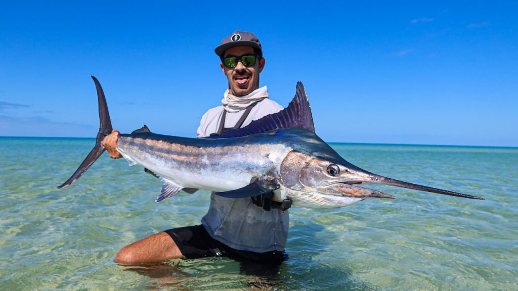 Jonny Brooks holding a black marlin on the beach