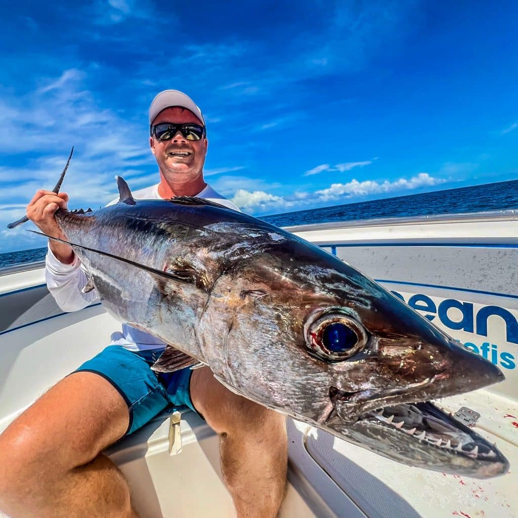 Angler holding a dogtooth tuna aboard an EdgeWater sport fisher in Vanuatu.