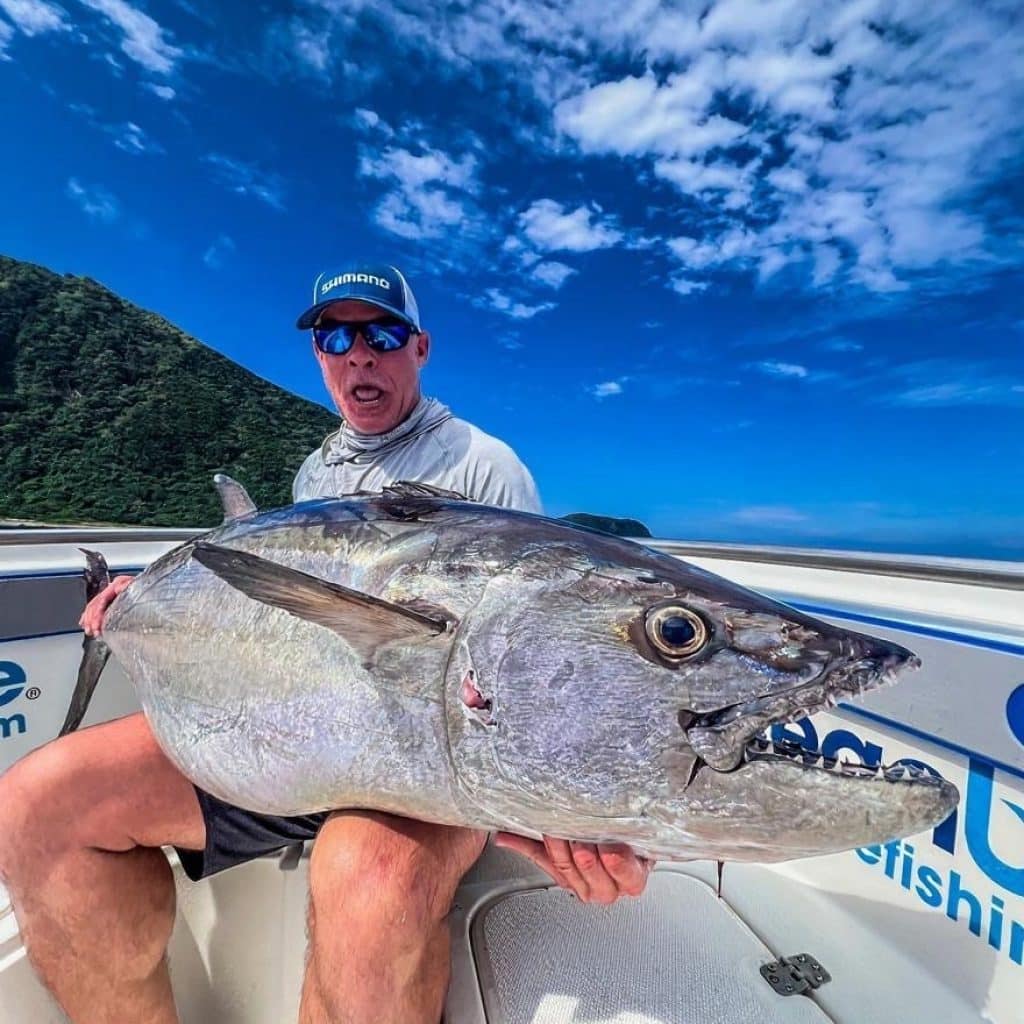 Fishing in Vanuatu September to December – Trophy Dogtooth Tuna | Ocean Blue Angler holding a trophy dogtooth tuna on a centre console in Vanuatu during the spring–summer season, part of fishing in Vanuatu September to December.