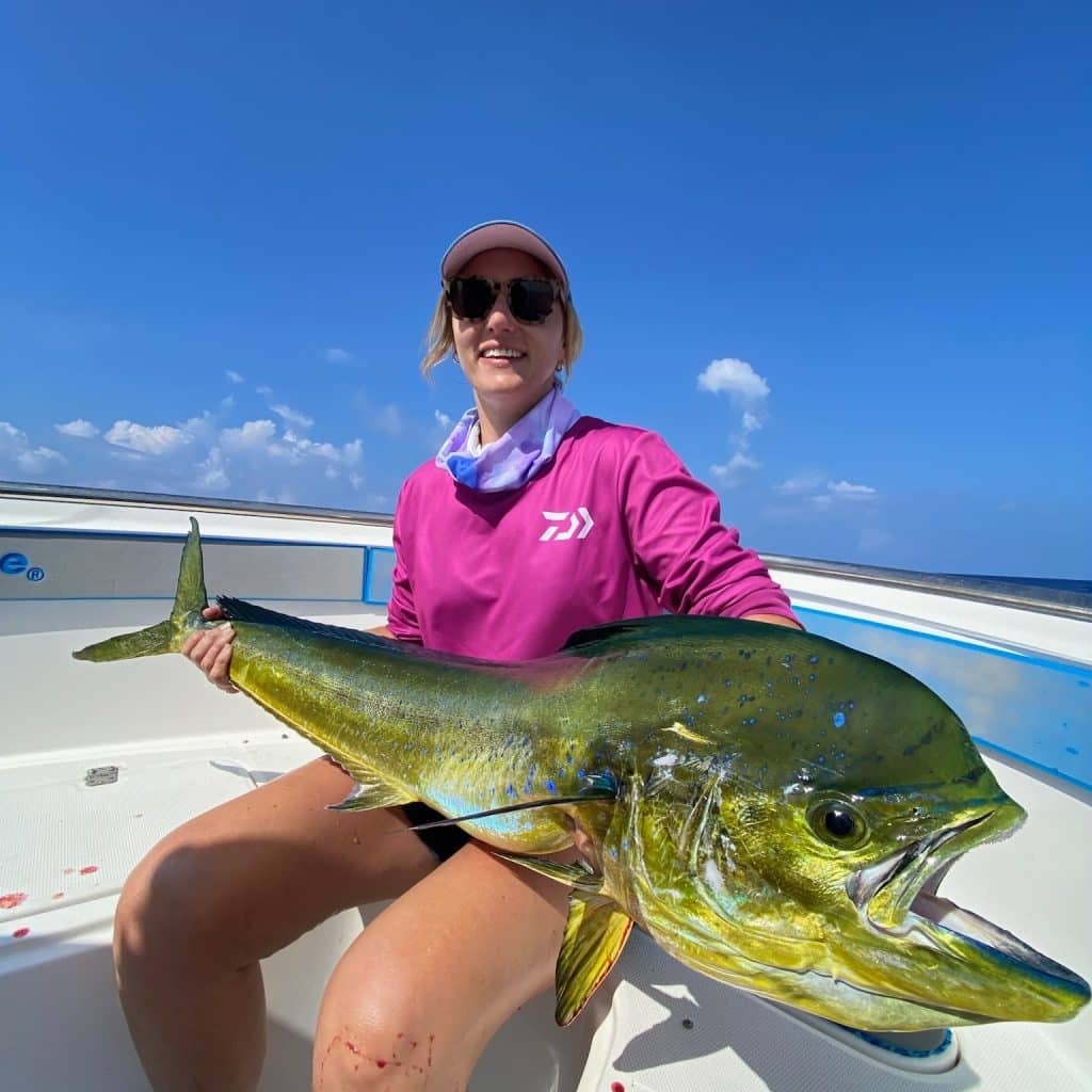 Angler holding a vibrant mahi‑mahi on an Ocean Blue centre console in Vanuatu with blue skies.