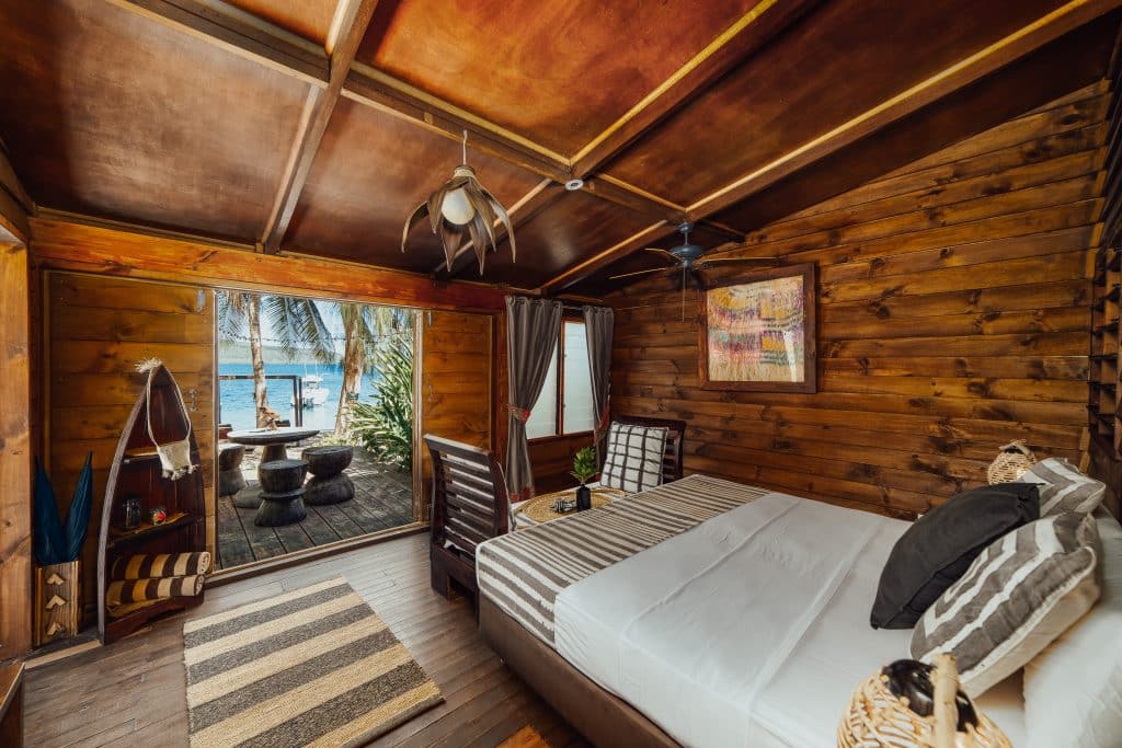 Timber waterfront bungalow interior at Trees & Fishes with sliding doors to a deck and boats on the bay.