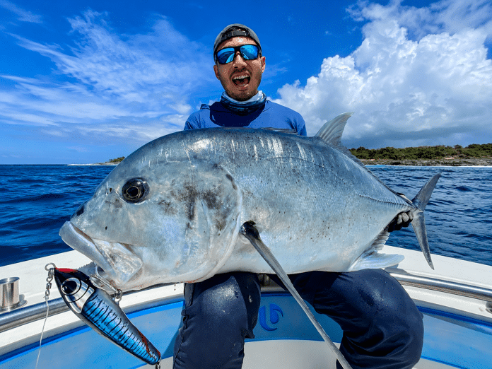 Angler holding it Giant Trevally on board one of our Edgewater 32ft Centre consoles expressing the excitement of the catch