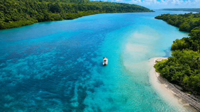 Fishing boat in Vanuatu's clear waters with tropical islands in the background