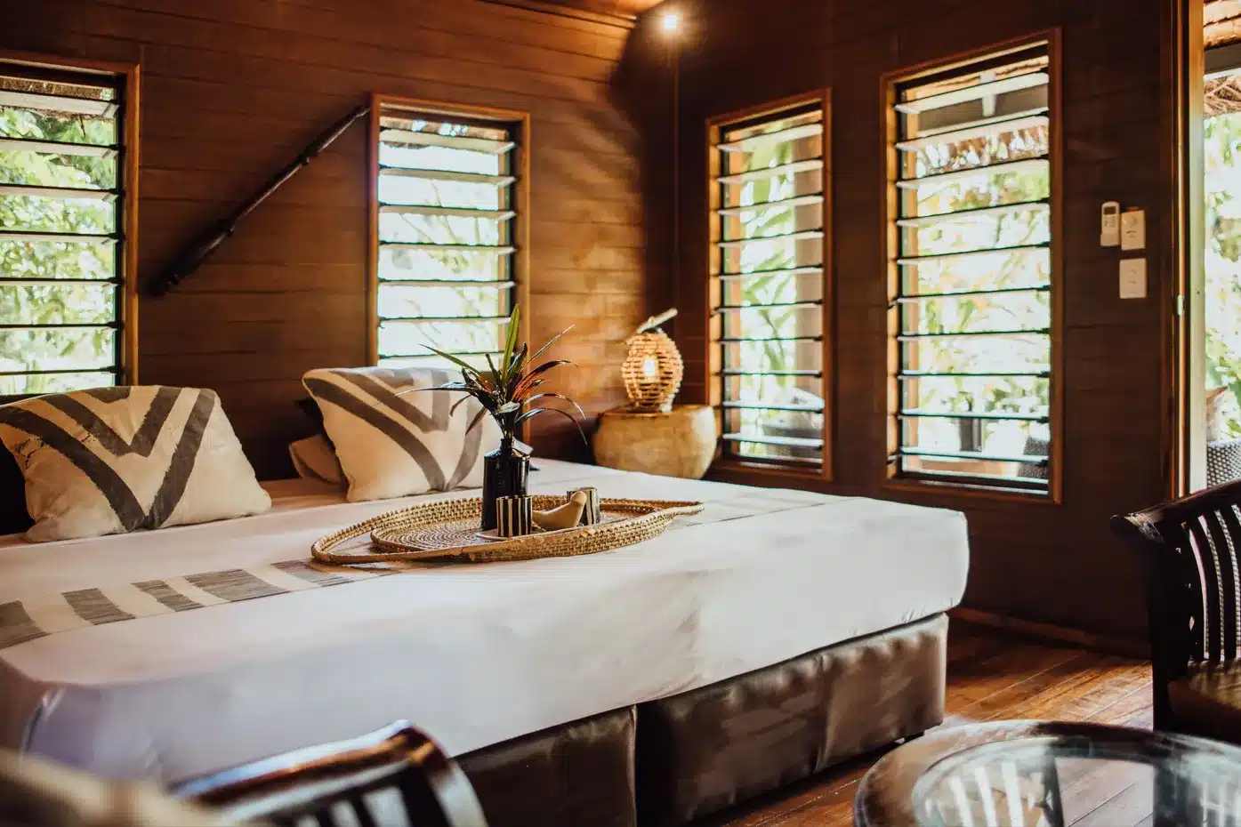 Garden Retreat Suite bedroom at Trees and Fishes Private Retreat in Port Havannah, Vanuatu, with a made-up bed, timber walls and louvre windows opening to tropical greenery.