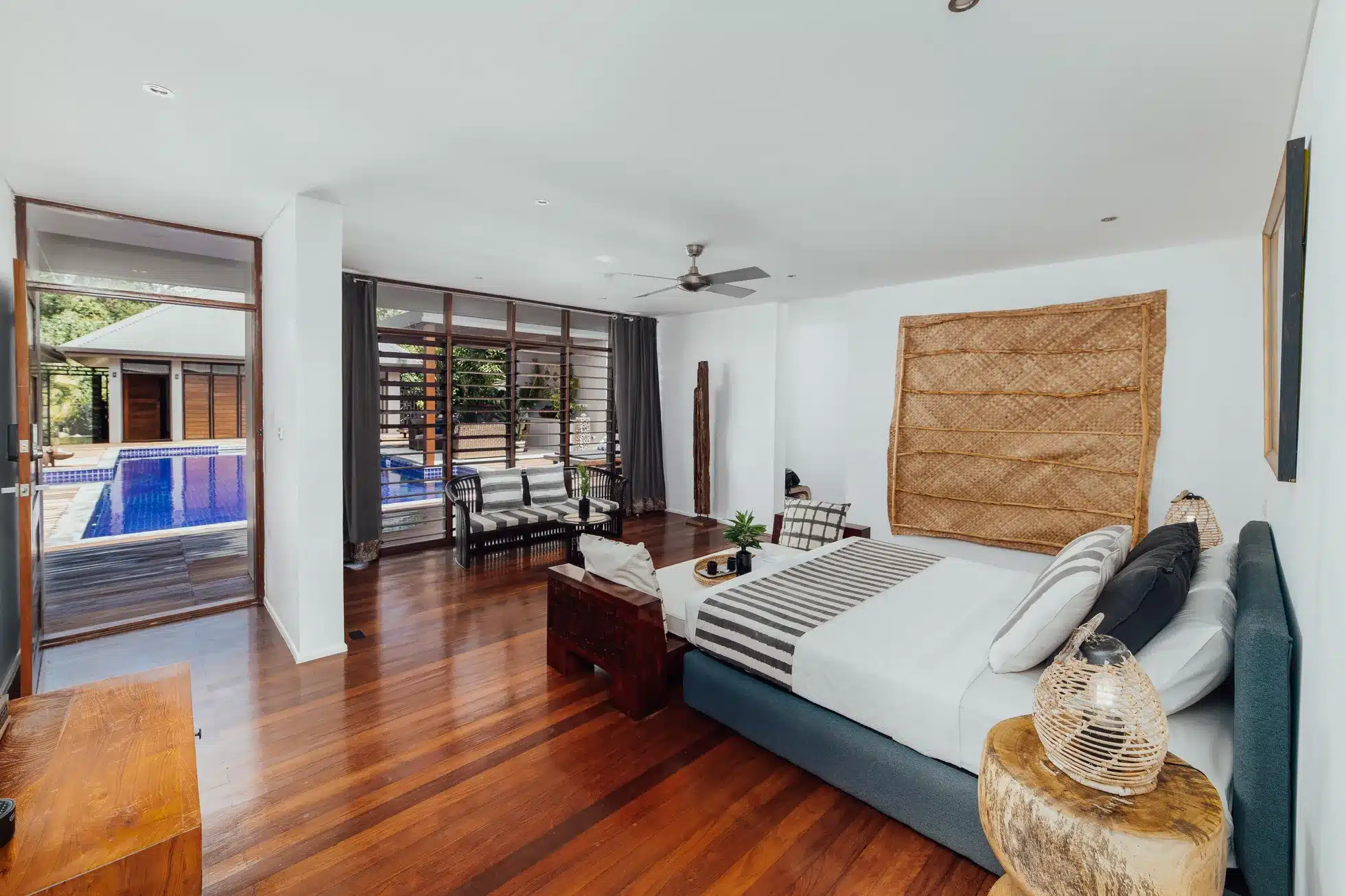 Interior of a luxury suite at Trees and Fishes Private Retreat in Port Havannah, Vanuatu, featuring timber floors, king bed, lounge seating and sliding doors opening to a private plunge pool.