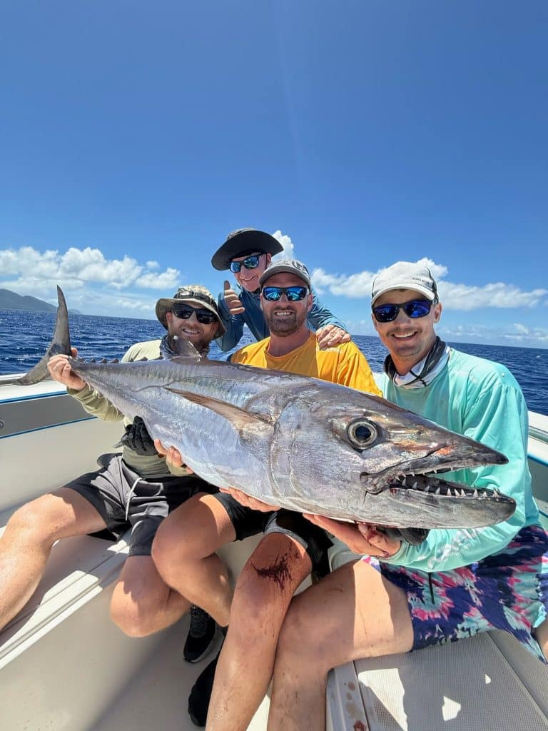Angler holding a trophy dogtooth tuna caught over Vanuatu volcanic reef drop-offs at golden hour