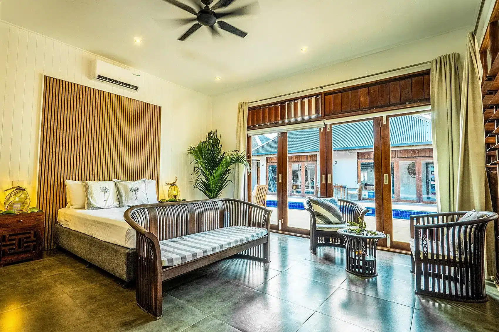 Villa Pool Suite at Trees and Fishes Private Retreat in Port Havannah, Vanuatu, showing a king bed, indoor seating area and large sliding doors opening to the pool courtyard.