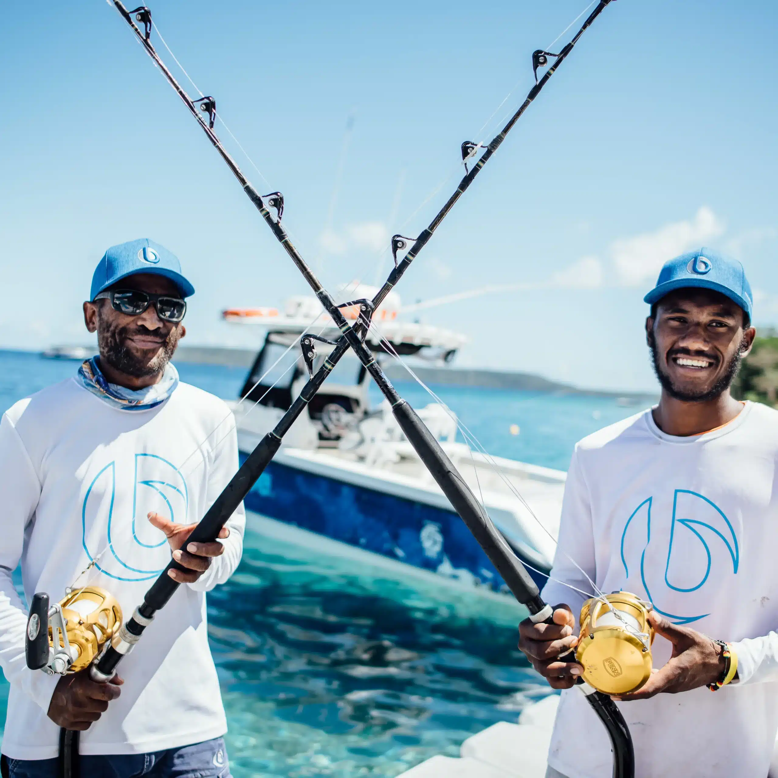 Two Ocean Blue Fishing Adventures crew members holding heavy tackle rods with gold reels on a boat in Vanuatu, ready for blue marlin fishing.