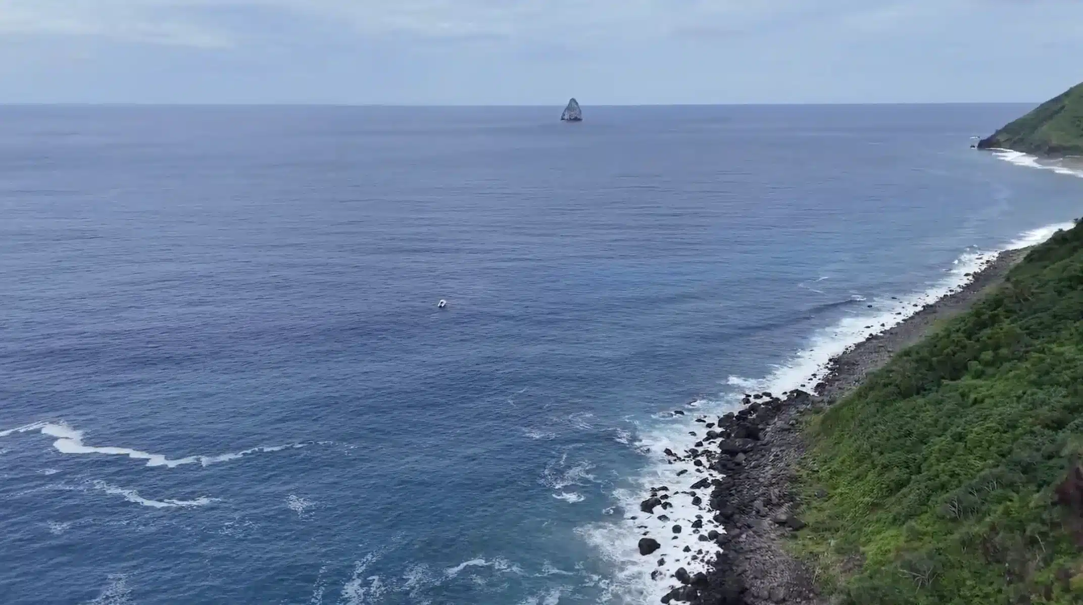 Aerial view of a rugged rocky coastline in Vanuatu with waves breaking along the shore and deep blue ocean stretching to the horizon.