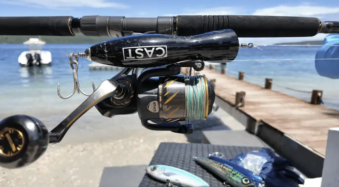 Close-up of a spinning reel and rod rigged with a popper lure and hooks on a jetty in Vanuatu, showing fishing tackle ready to use.