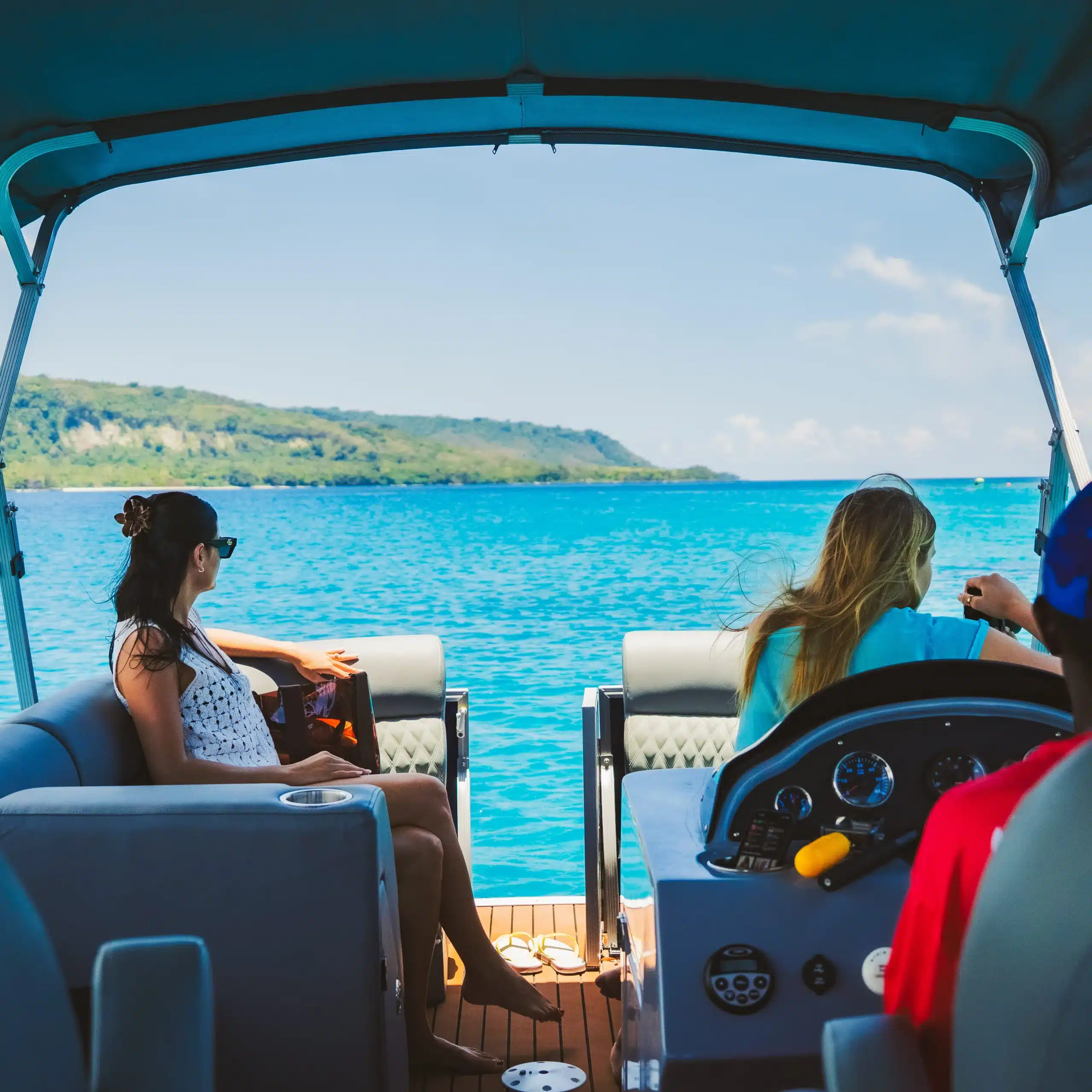Guests relaxing on a boat in Vanuatu with bright turquoise water and island coastline ahead, showing a scenic cruise for anglers and non-anglers.