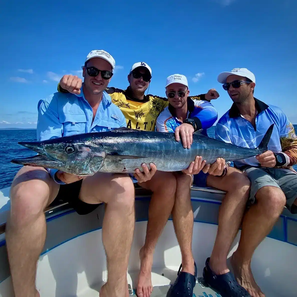 Group of anglers holding a large wahoo on a boat in Vanuatu, posing on open water after a successful reef-edge fishing session.