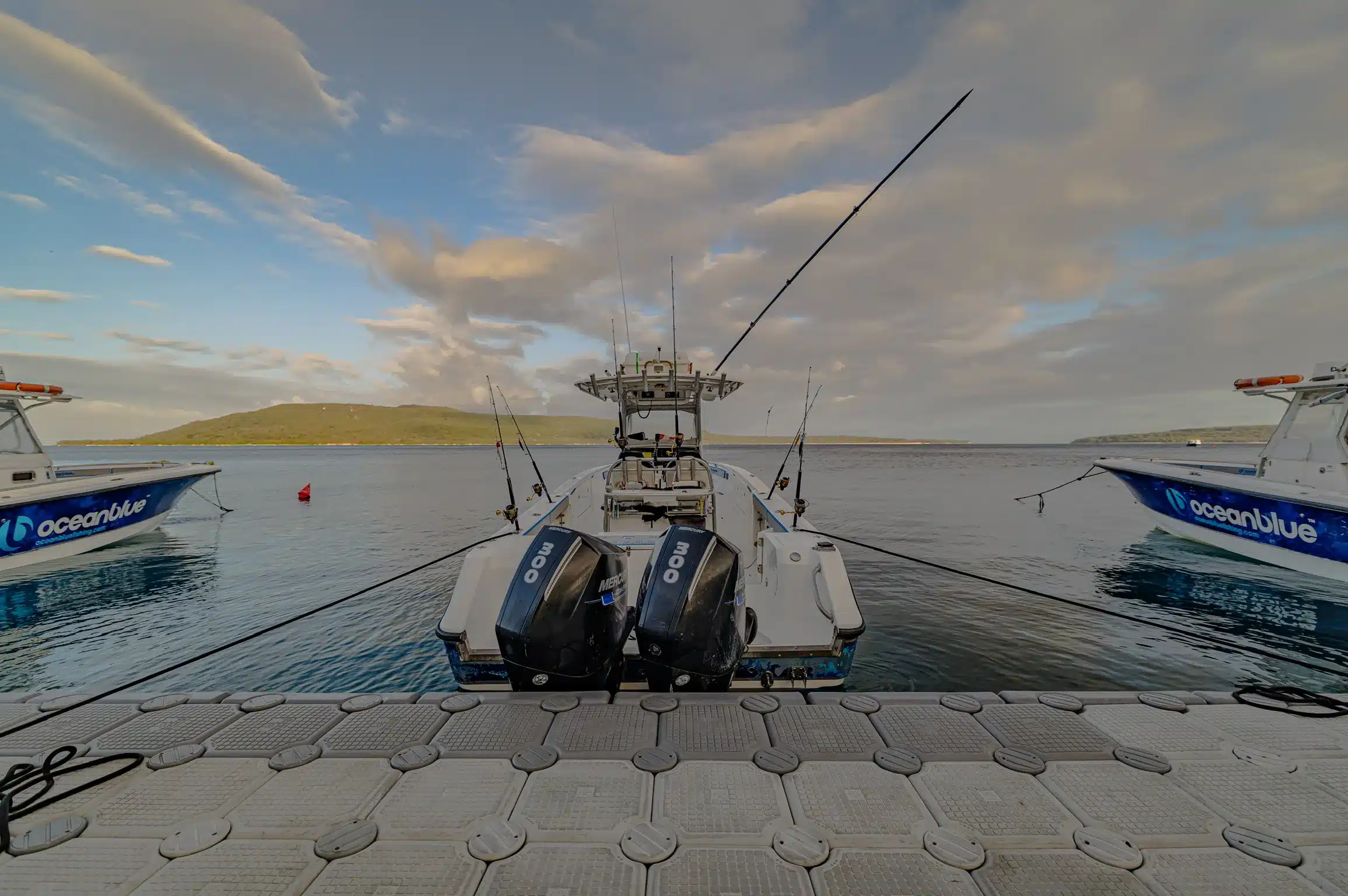 EdgeWater 318CC sport fishing boat moored at a jetty in Vanuatu, viewed from the stern with twin outboards and rods rigged.